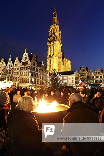 People drinking mulled wine around a big gas flame campfire  Christmas market at the town hall on Grote Markt  surrounded by old guild houses  historic centre of Antwerp  Flanders  Belgium  Europe