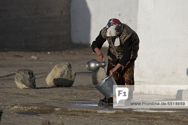 Kirgisin wäscht Blecheimer mit Wasserkaraffe aus  in Alichur am Pamir-Highway M41  Ost-Pamir  Tadschikistan  Zentralasien