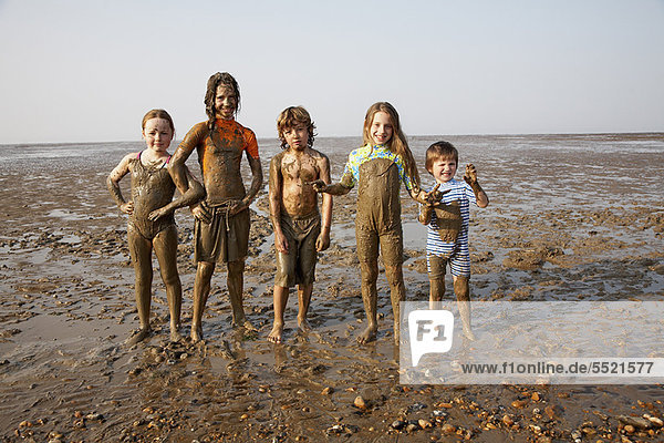 Children covered in mud on rocky beach