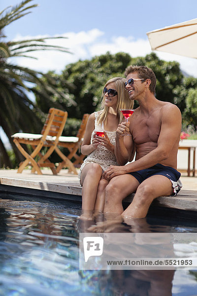Couple toasting each other by pool