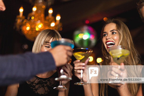 Lächelnde Frauen beim Cocktail im Club