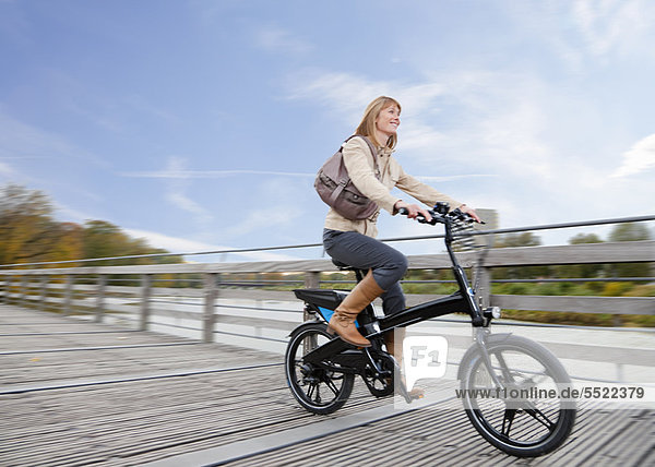 Frau fährt Fahrrad auf Holzsteg