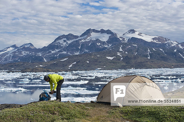 Hiker  tent  ice floes and mountains  Tasiilaq or Ammassalik  East Greenland