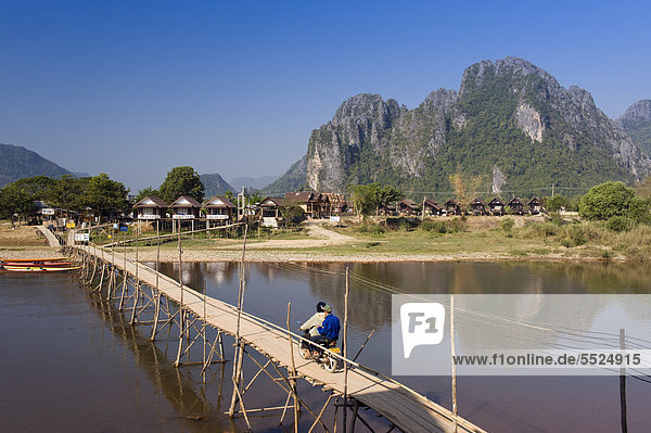 Bamboo bridge with moped rider over the Nam Song River  karst mountains  Vang Vieng  Vientiane  Laos  Indochina  Asia