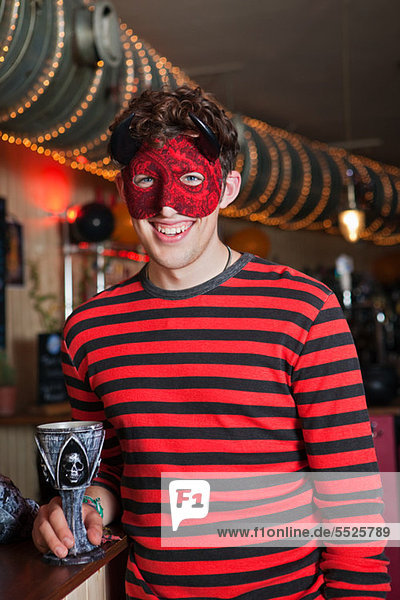 Junger Mann in Kostüm und Maske in bar  Porträt