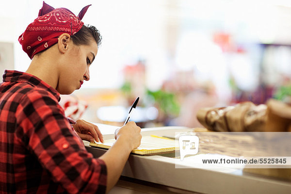 Junge Frau beim Schreiben auf der Theke der Bäckerei