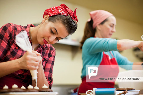 Junge Frau mit Spritzbeutel in der Bäckerei
