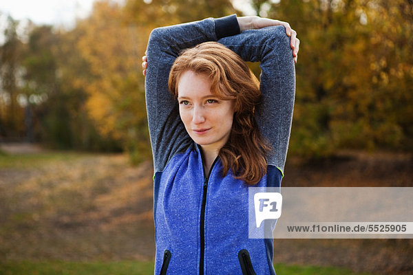 Young woman performing stretches in park