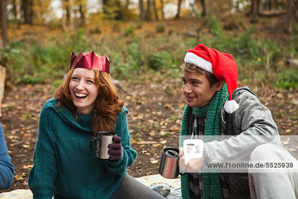 Young couple wearing Santa hats and crowns in forest