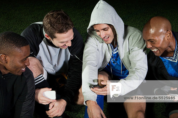 Fußballspieler beim Blick auf das Handy auf dem Spielfeld