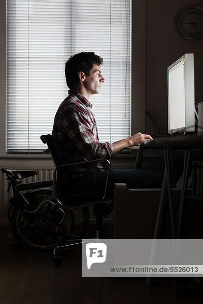 Mitte erwachsenen Mann mit Computer zu Hause am Schreibtisch