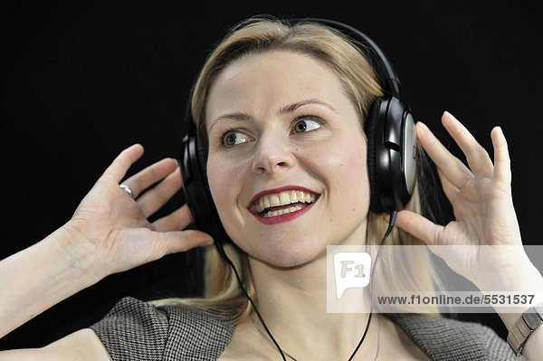 Junge Frau hört mit Kopfhörer begeistert Musik