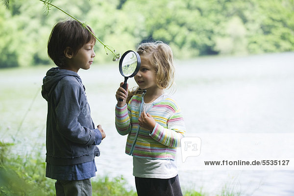 Children playing with magnifying glass outdoors
