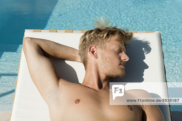 Mann beim Sonnenbaden am Pool
