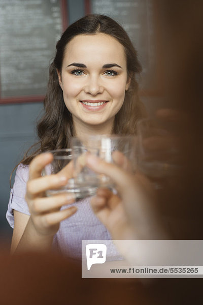 Junge Frau  die mit einem Freund Glas erhebt