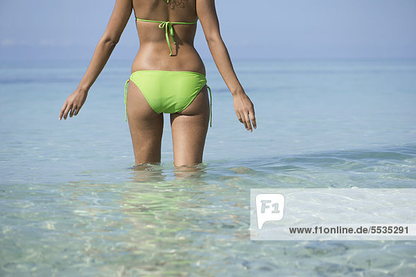 Frau im Bikini im Wasser stehend  Mittelteil