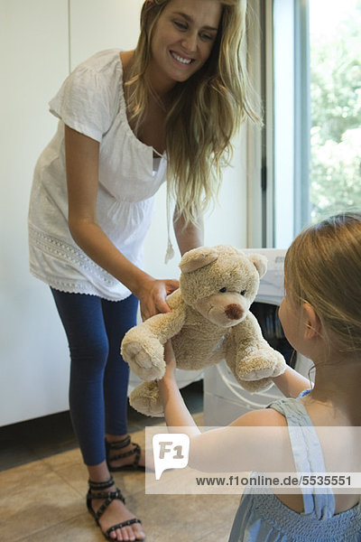 Mutter übergibt frisch geputzten Teddybär an kleines Mädchen