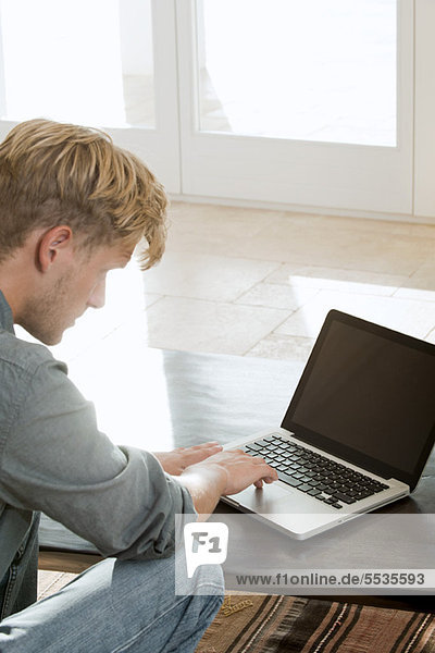 Mann mit Laptop-Computer zu Hause