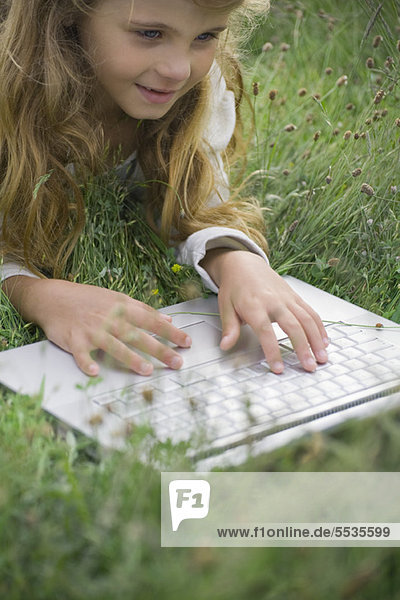 Girl lying in grass  using laptop computer