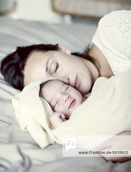 Mother and new born baby sleeping in bed