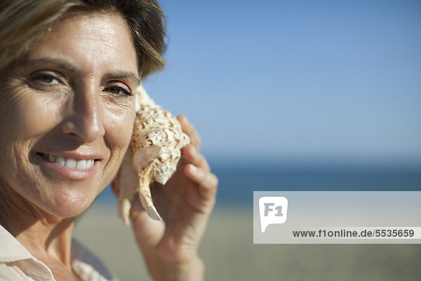 Woman listening to seashell  portrait