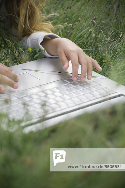 Girl lying in grass  using laptop computer