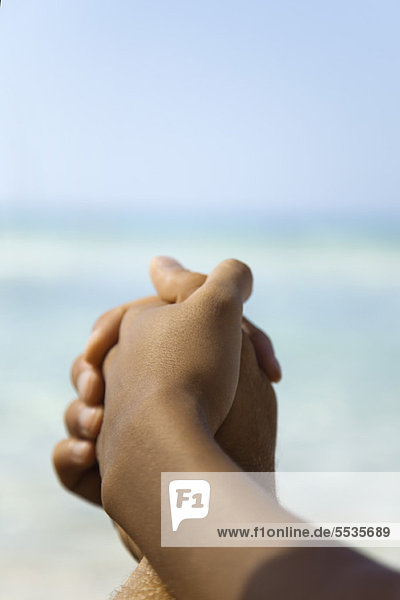 Paar hält sich am Strand an den Händen  abgeschnitten