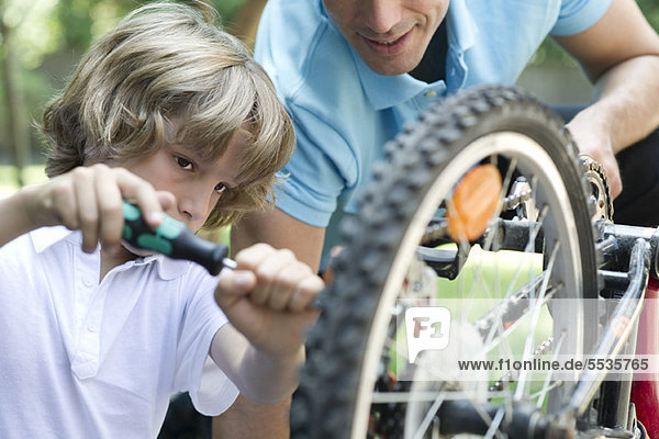 Junge repariert Fahrrad mit Vaters Hilfe
