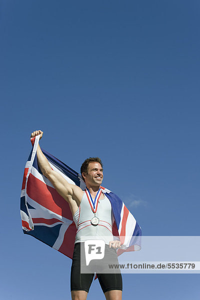 Männlicher Athlet auf dem Siegerpodest mit britischer Flagge