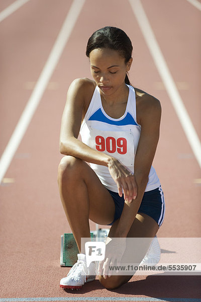 Female runner crouching at starting line with eyes closed