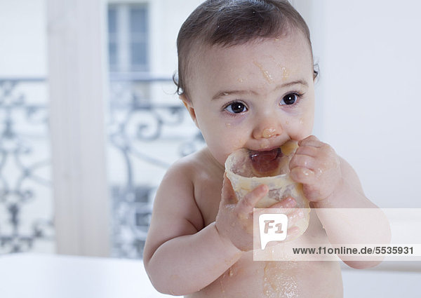 Säuglingsbeißender Plastikbehälter mit Lebensmittelüberzug  Portrait