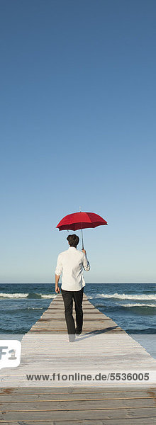 Mann auf dem Pier mit Regenschirm
