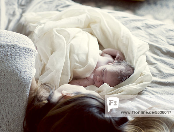 Neugeborenes Baby und Mutter im Bett liegend