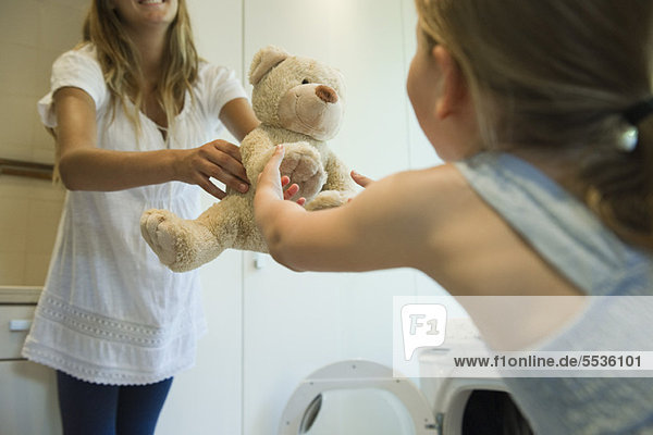 Kleines Mädchen erhält frisch geputztes Teddybärchen von Mutter