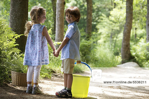 Children holding hands on path in woods