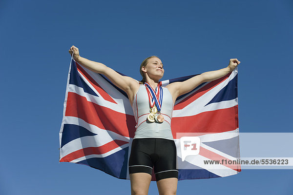 Athletin  die auf dem Podium geehrt wird und die britische Flagge hochhält.