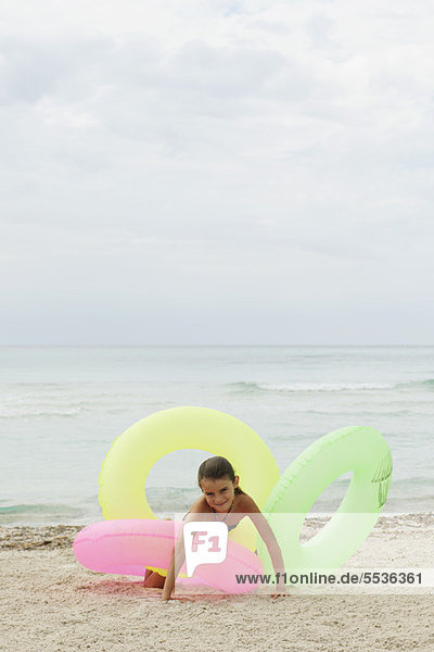 Mädchen spielen mit aufblasbaren Ringen am Strand