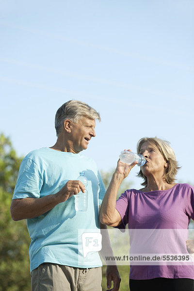 Seniorenpaar trinkt Flaschenwasser im Freien