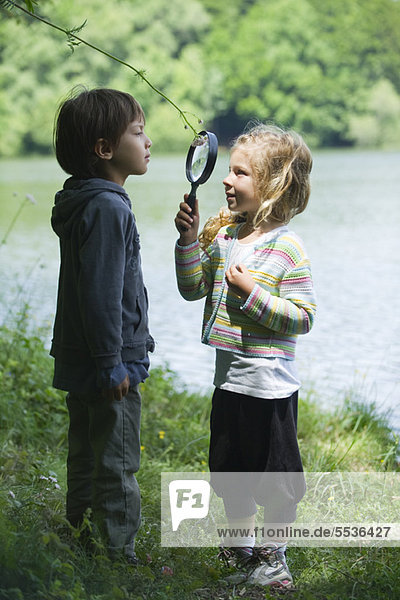 Children playing with magnifying glass outdoors