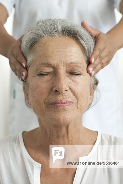 Senior woman having her temples massaged  cropped