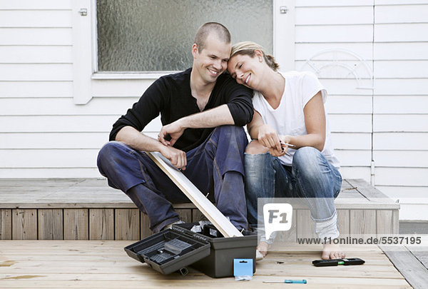 Woman leaning on man's shoulder while renovating their house