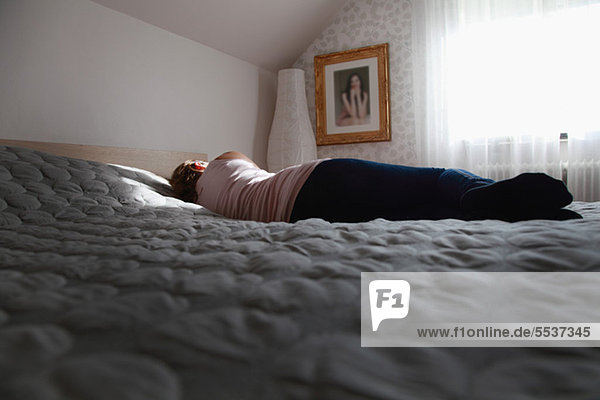 Rear view of woman lying on bed
