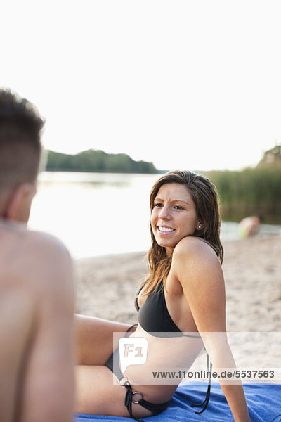Schöne junge Frau im Bikini  die den Mann am Strand ansieht.