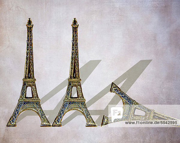 Drei Mini-Eiffeltürme  geformt wie der Buchstabe A  einer davon umgefallen  symbolisches Bild für die Herabstufung der AAA-Rating Frankreichs