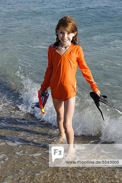 Girl with snorkeling gear  flippers and goggles on a beach by the sea