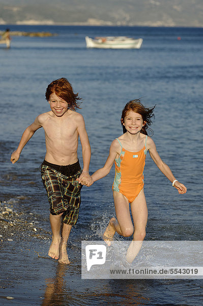 Siblings running on the beach  happy  Samos island  southern Sporades  Aegean sea  Greece  Europe