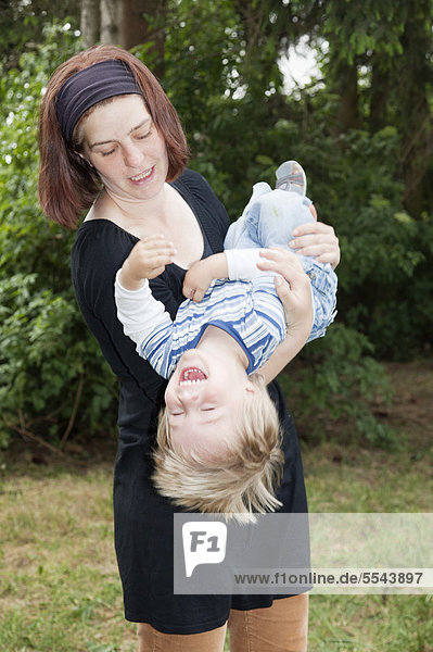 Mutter wirbelt ihren zweijährigen Sohn durch die Luft