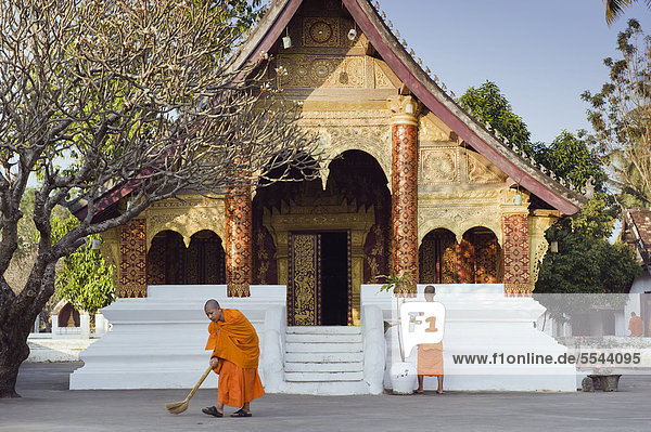 Mönche kehren am Morgen den Tempel  Wat Sibounheuang  Luang Prabang  UNESCO-Weltkulturerbe  Laos  Indochina  Asien