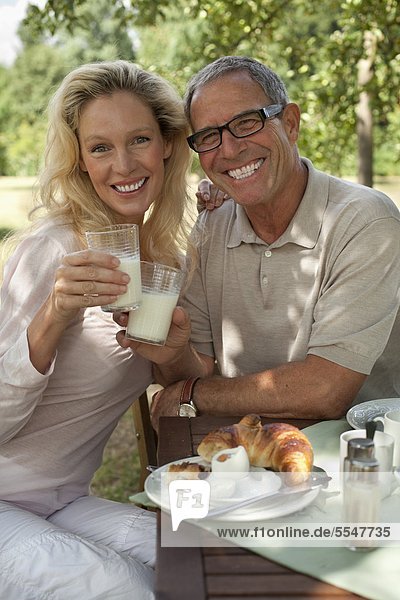 Smiling mature couple outdoors at breakfast table