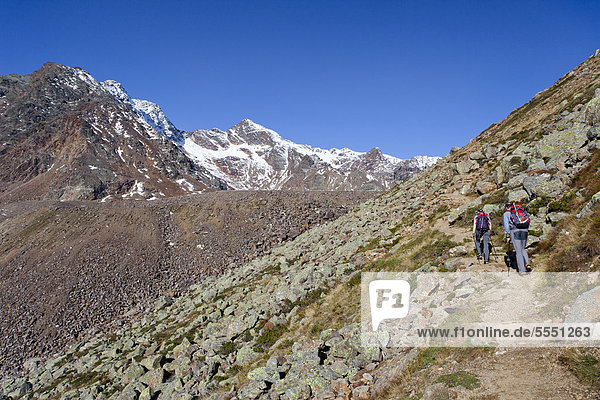 Hikers ascending Hintere Eggenspitz Mountain in Ulten Valley above the Weissbrunnsee lake  looking towards Weissbrunnspitze Mountain with the summit Hintere Eggenspitz Mountain on the left  Alto Adige  Italy  Europe